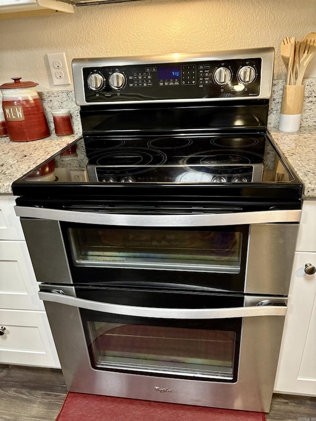 135 Meadow Dr, Beebe, AR 72012 - kitchen view of range with two ovens, white cabinets, wood finished floors, and light stone countertops