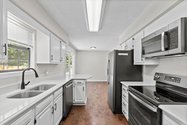 1214 Sammy St, Mountain Home, AR 72653 - kitchen featuring appliances with stainless steel finishes, a sink, a textured ceiling, a peninsula, and white cabinetry