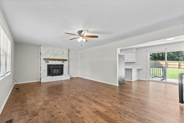 1214 Sammy St, Mountain Home, AR 72653 - unfurnished living room featuring a ceiling fan, wood finished floors, baseboards, and a stone fireplace