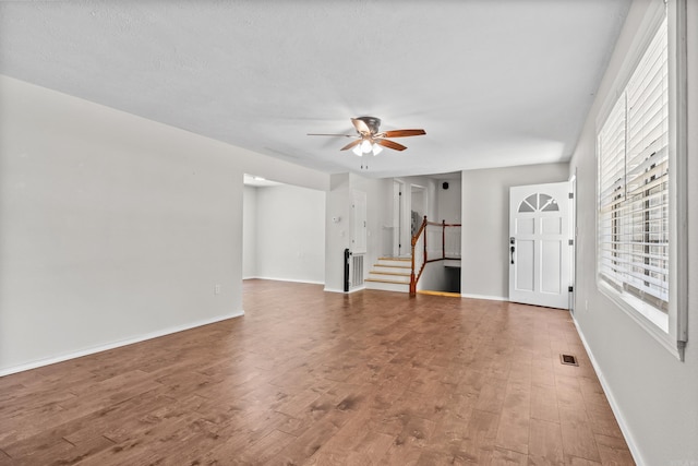 1214 Sammy St, Mountain Home, AR 72653 - unfurnished living room featuring a ceiling fan, stairs, wood finished floors, and baseboards