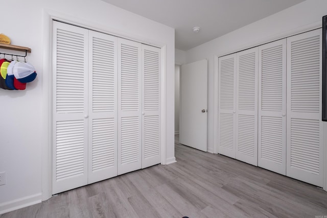 4605 N Cedar, North Little Rock, AR 72116 - unfurnished bedroom with wood finished floors, baseboards, and two closets