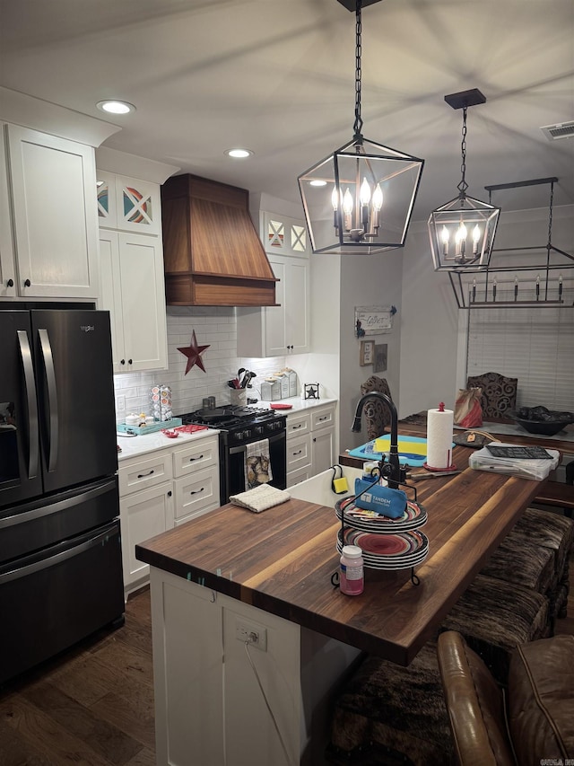 1927 College Ave, Conway, AR 72034 - kitchen with black appliances, custom range hood, butcher block countertops, decorative backsplash, and dark wood-type flooring