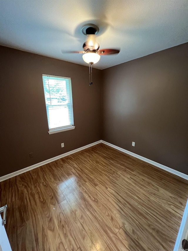 empty room with a ceiling fan, wood finished floors, and baseboards