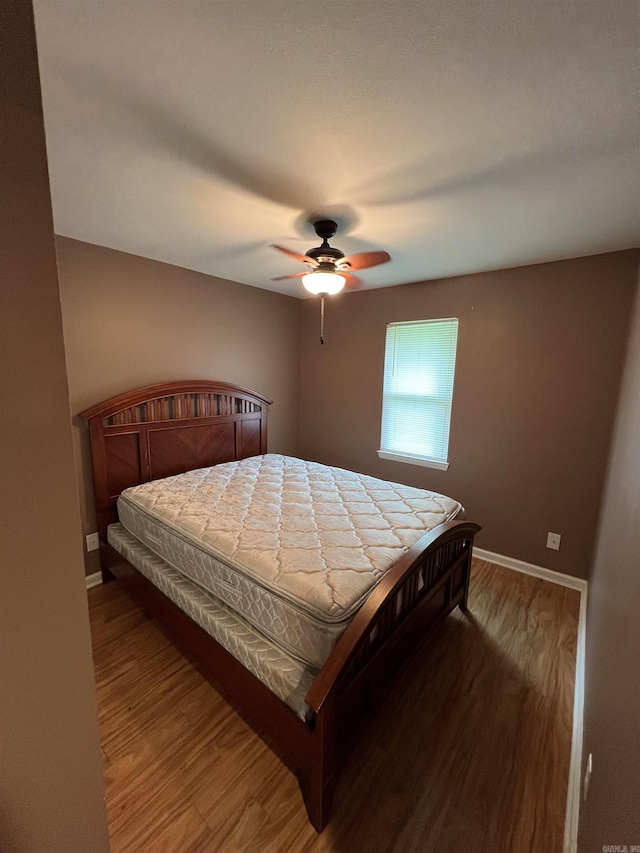 bedroom with wood finished floors, baseboards, and ceiling fan