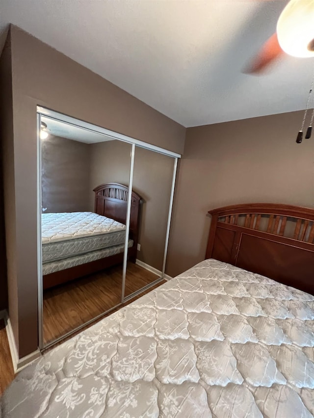 bedroom with wood finished floors, a ceiling fan, a closet, and baseboards