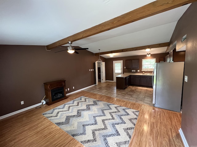 kitchen with freestanding refrigerator, light wood-style flooring, dark brown cabinets, light countertops, and beam ceiling