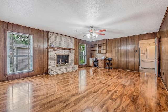 4204 Fox Hill Rd, North Little Rock, AR 72116 - unfurnished living room featuring a textured ceiling, wooden walls, an office area, a ceiling fan, and wood finished floors