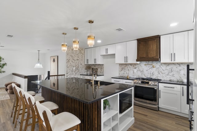 7 Buttermilk Rd, Little Rock, AR 72227 - kitchen with stainless steel range with gas stovetop, a sink, backsplash, dark wood finished floors, and a kitchen breakfast bar