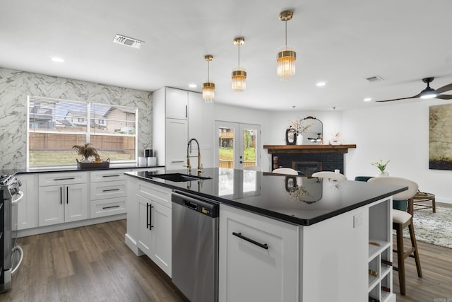 7 Buttermilk Rd, Little Rock, AR 72227 - kitchen featuring appliances with stainless steel finishes, a sink, dark countertops, white cabinetry, and an island with sink