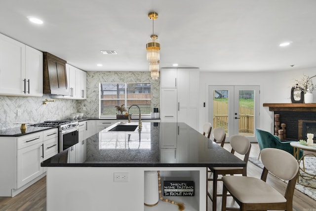 7 Buttermilk Rd, Little Rock, AR 72227 - kitchen featuring a sink, stainless steel range with gas cooktop, custom range hood, tasteful backsplash, and an island with sink