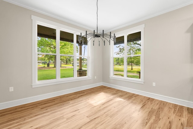 unfurnished dining area with a chandelier, crown molding, baseboards, and light wood-style flooring