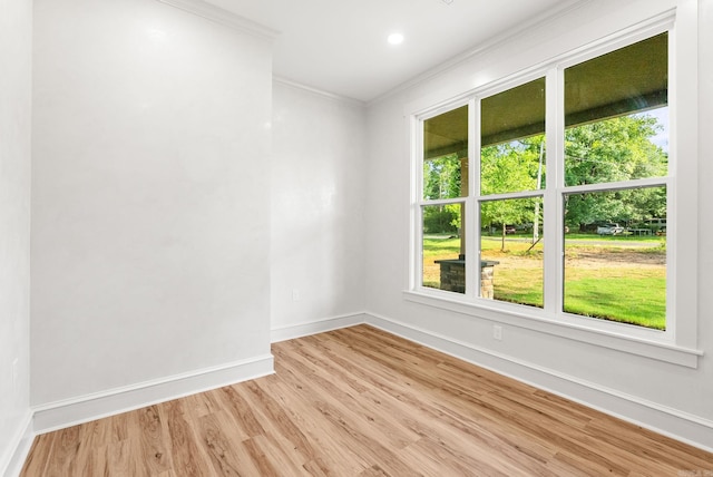 empty room with ornamental molding, healthy amount of natural light, baseboards, light wood finished floors, and recessed lighting