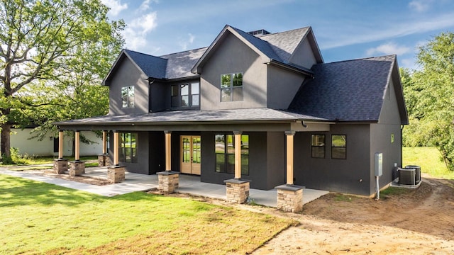 rear view of house featuring stucco siding, roof with shingles, a lawn, and central AC