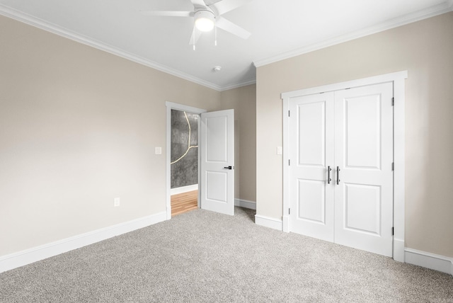 unfurnished bedroom featuring crown molding, carpet, a closet, baseboards, and ceiling fan