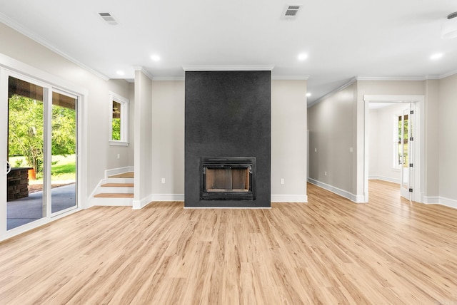 unfurnished living room with a large fireplace, plenty of natural light, light wood-style flooring, ornamental molding, and baseboards