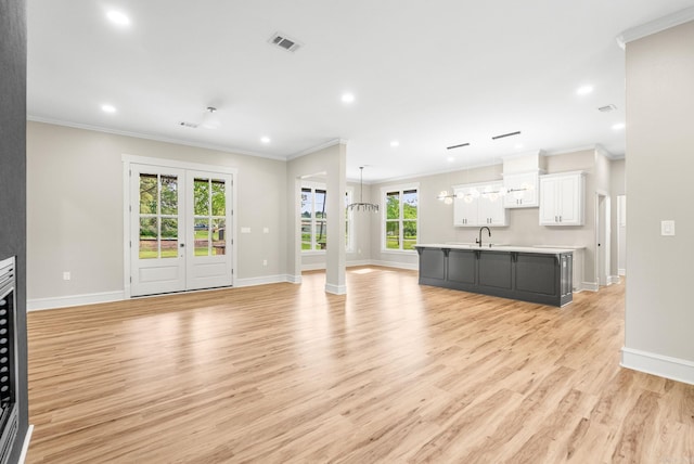 unfurnished living room with a sink, ornamental molding, light wood-style flooring, recessed lighting, and baseboards