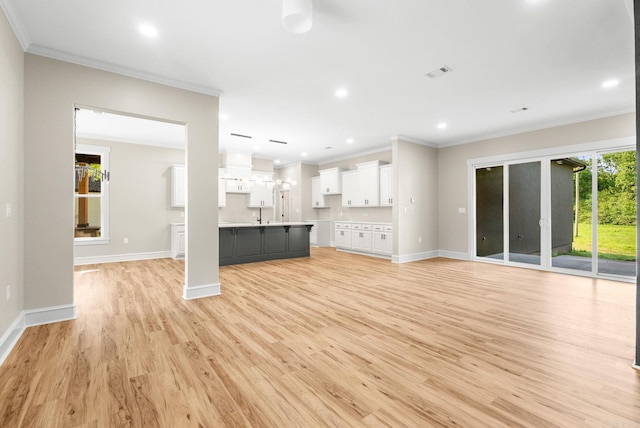 unfurnished living room featuring crown molding, light wood-style flooring, baseboards, and recessed lighting