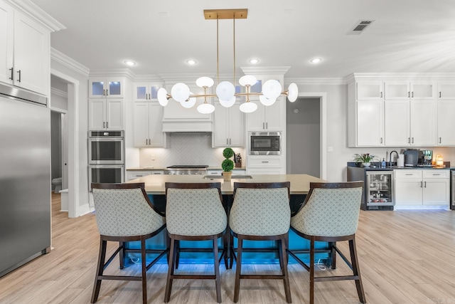 67 Falstone Dr, Little Rock, AR 72223 - kitchen with built in appliances, beverage cooler, white cabinets, crown molding, and recessed lighting