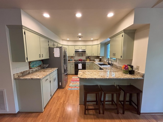 36C Peninsula Dr Unit C, Mount Ida, AR 71957 - kitchen with range with gas cooktop, a peninsula, a sink, under cabinet range hood, and light wood-type flooring