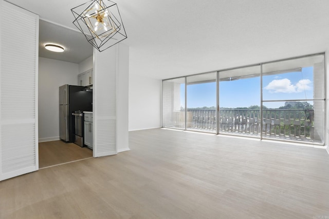 700 E 9th J St, Little Rock, AR 72202 - empty room with light wood-style floors, floor to ceiling windows, a chandelier, and baseboards