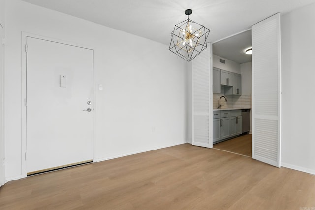 700 E 9th J St, Little Rock, AR 72202 - unfurnished dining area featuring a chandelier, light wood-style flooring, baseboards, and a sink
