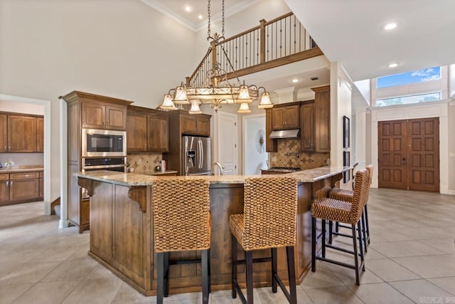 34 Chemin Ct, Little Rock, AR 72223 - kitchen with appliances with stainless steel finishes, under cabinet range hood, a high ceiling, ornamental molding, and tasteful backsplash