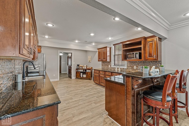 3117 Meador Ave, Jonesboro, AR 72401 - kitchen with crown molding, a sink, stainless steel microwave, brown cabinets, and a peninsula