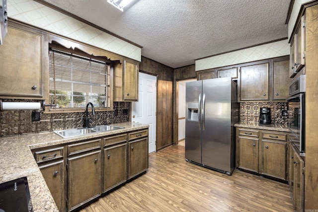 817 Ouachita Pl, Little Rock, AR 72205 - kitchen featuring stainless steel appliances, a sink, decorative backsplash, light wood finished floors, and a textured ceiling