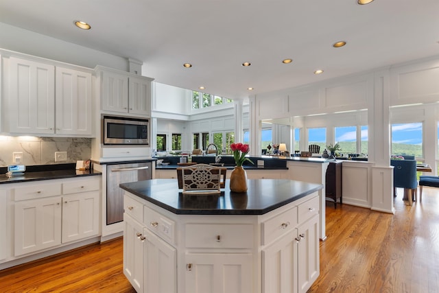 4501 Ridgefield Ln, Little Rock, AR 72223 - kitchen with appliances with stainless steel finishes, a kitchen island, dark countertops, light wood-style floors, and backsplash
