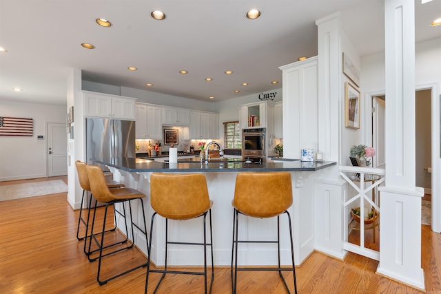4501 Ridgefield Ln, Little Rock, AR 72223 - kitchen featuring white cabinetry, light wood finished floors, a peninsula, recessed lighting, and a breakfast bar area