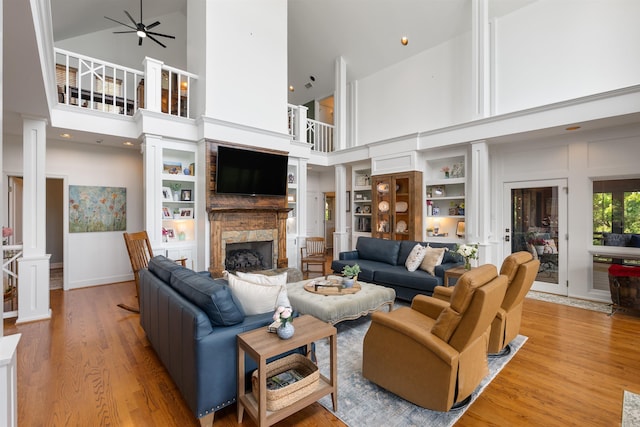 4501 Ridgefield Ln, Little Rock, AR 72223 - living area with high vaulted ceiling, ceiling fan, wood finished floors, a stone fireplace, and ornate columns