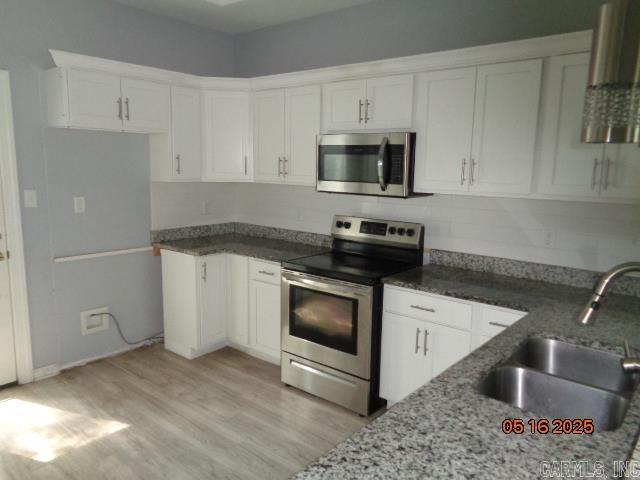 3122 Main St, Little Rock, AR 72206 - kitchen featuring appliances with stainless steel finishes, a sink, white cabinetry, light wood-style flooring, and light stone countertops