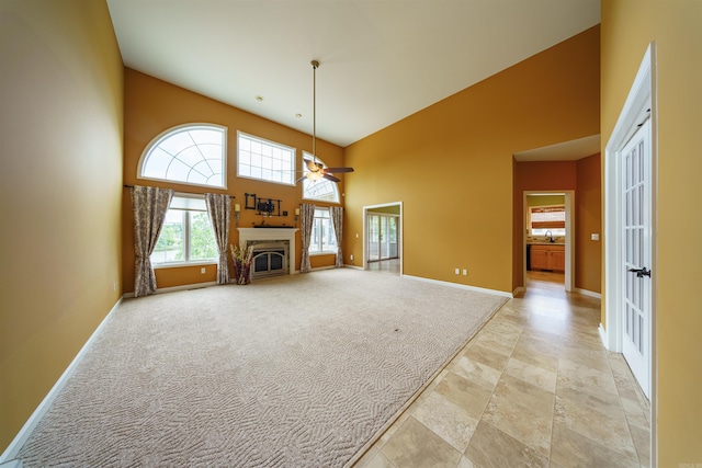 505 E Tri Lks, Horseshoe Bend, AR 72512 - unfurnished living room featuring baseboards, a towering ceiling, a fireplace, ceiling fan, and light carpet