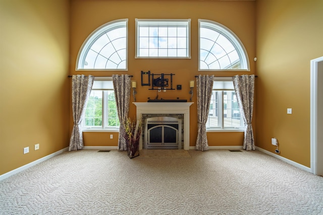 505 E Tri Lks, Horseshoe Bend, AR 72512 - unfurnished living room with a towering ceiling, carpet, a tile fireplace, and baseboards