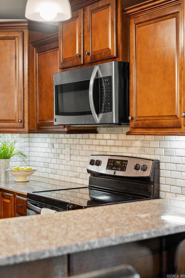 390 Bobwhite Cir, Lonoke, AR 72086 - kitchen featuring stainless steel appliances, brown cabinetry, and tasteful backsplash