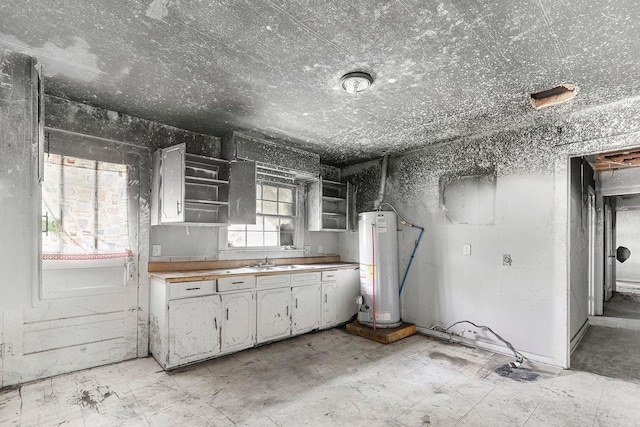 818 W 25th St, North Little Rock, AR 72114 - kitchen featuring gas water heater, a sink, light floors, white cabinetry, and open shelves
