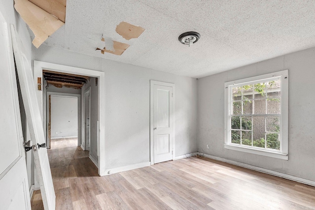 818 W 25th St, North Little Rock, AR 72114 - unfurnished bedroom with light wood-type flooring, a textured ceiling, and baseboards
