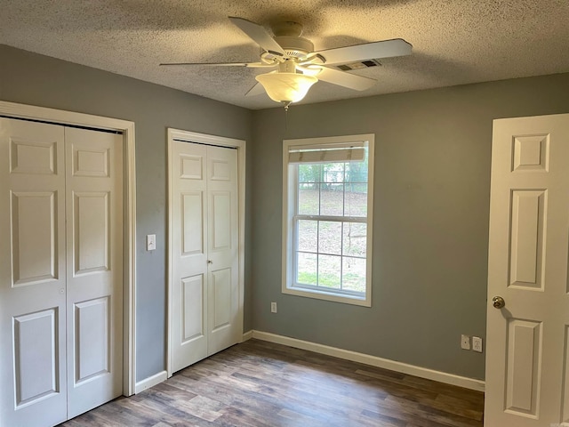 417 Ridge Rd, Pocahontas, AR 72455 - unfurnished bedroom featuring wood finished floors, two closets, baseboards, a textured ceiling, and a ceiling fan