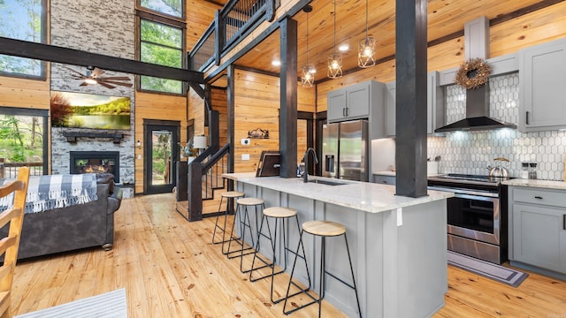 136 Gnarly Maple Trl, Hochatown, OK 74728 - kitchen with stainless steel appliances, gray cabinets, light wood-style flooring, backsplash, and wood walls