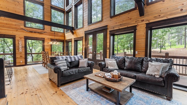 136 Gnarly Maple Trl, Hochatown, OK 74728 - living room with french doors, wooden walls, plenty of natural light, a towering ceiling, and light wood-type flooring