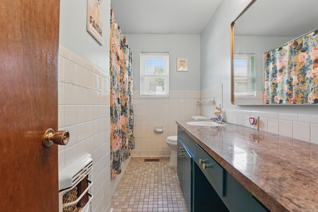 415 W 50th St, North Little Rock, AR 72118 - bathroom with toilet, tile walls, vanity, tile patterned flooring, and a wainscoted wall