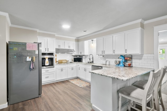 3101 Lax St, Newport, AR 72112 - kitchen featuring appliances with stainless steel finishes, under cabinet range hood, a sink, a peninsula, and ornamental molding
