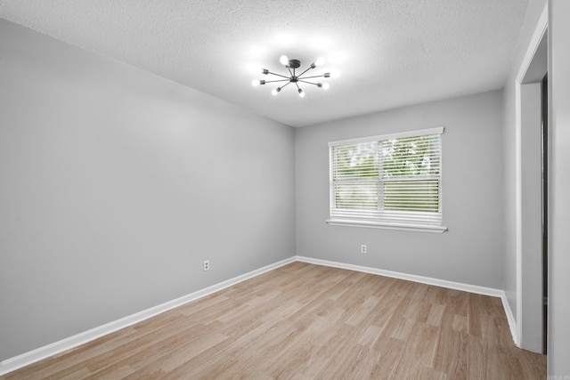 12224 Shawnee Forest Dr, Little Rock, AR 72212 - spare room featuring light wood-style flooring, a chandelier, a textured ceiling, and baseboards