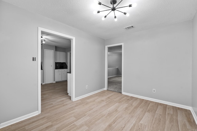 12224 Shawnee Forest Dr, Little Rock, AR 72212 - unfurnished bedroom featuring light wood-style floors, a chandelier, baseboards, and a textured ceiling