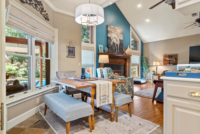 dining space with a ceiling fan, a warm lit fireplace, high vaulted ceiling, recessed lighting, and baseboards