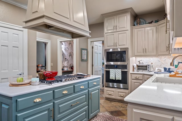 kitchen with stainless steel gas cooktop, a sink, light countertops, built in microwave, and blue cabinetry