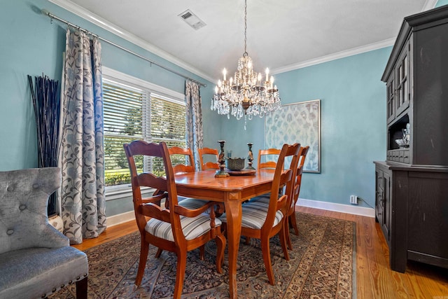 dining room featuring a chandelier, ornamental molding, wood finished floors, and baseboards