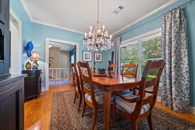dining space with a chandelier, light wood-style floors, crown molding, and baseboards