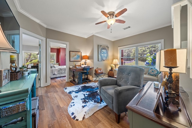living area with ceiling fan, wood finished floors, and ornamental molding