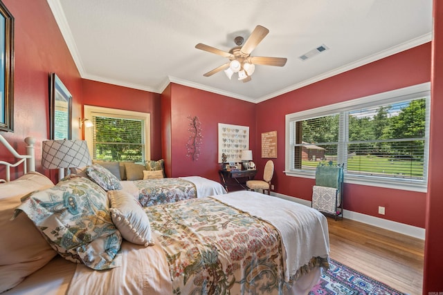 bedroom featuring wood finished floors, crown molding, baseboards, and a ceiling fan